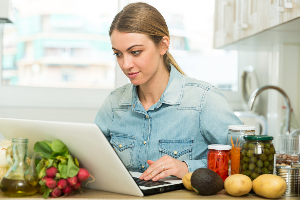 A woman surrounded by food using a laptop