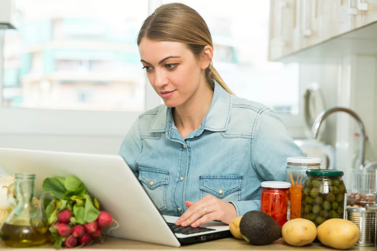 A woman surrounded by food using a laptop